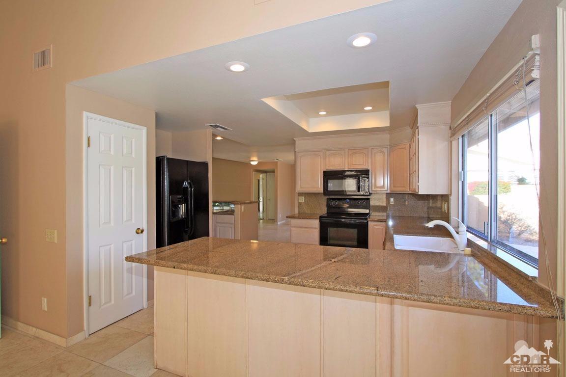 72957 Haystack Road Palm Desert, CA 92260 - Photo 30 of 38 a kitchen with stainless steel appliances kitchen island granite countertop a refrigerator and a sink