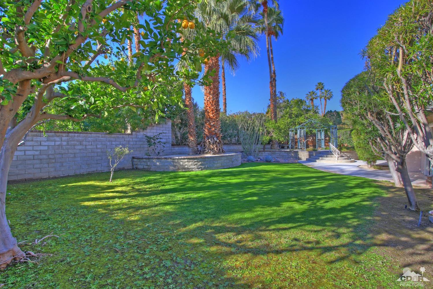 72957 Haystack Road Palm Desert, CA 92260 - Photo 6 of 38 a backyard of a house with lots of green space and fountain