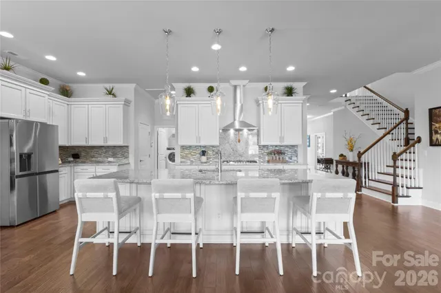 a kitchen with stainless steel appliances kitchen island granite countertop a table chairs and a dining table