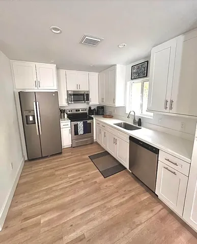 a kitchen with stainless steel appliances granite countertop a sink stove refrigerator and cabinets
