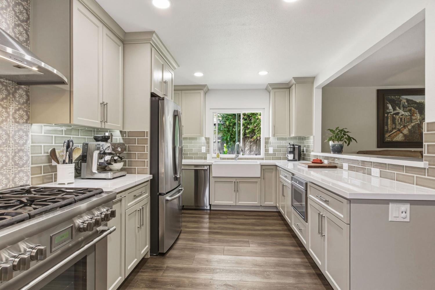 2882 El Camino Real Merced, CA 95340 - Photo 10 of 32 a kitchen with stainless steel appliances granite countertop a stove a sink dishwasher a refrigerator and white cabinets with wooden floor