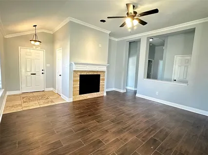 a view of an empty room with wooden floor and a fireplace