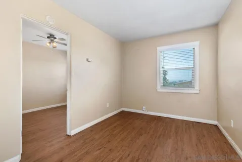 an empty room with wooden floor and entrance to ceiling window