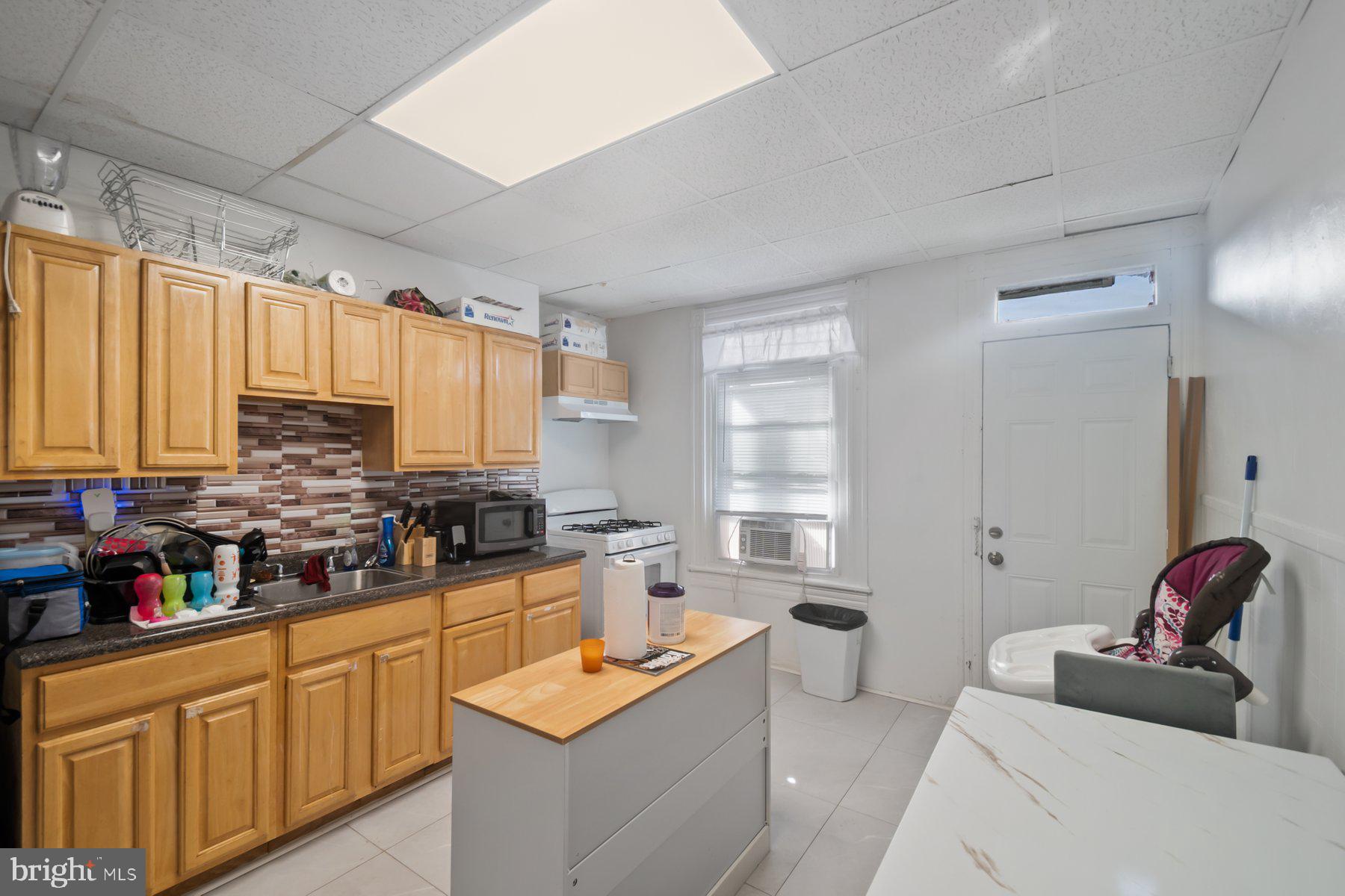 1659 Cliftview Avenue Baltimore, MD 21213 - Photo 8 of 25 a kitchen with stainless steel appliances a sink dishwasher stove and white cabinets with wooden floor
