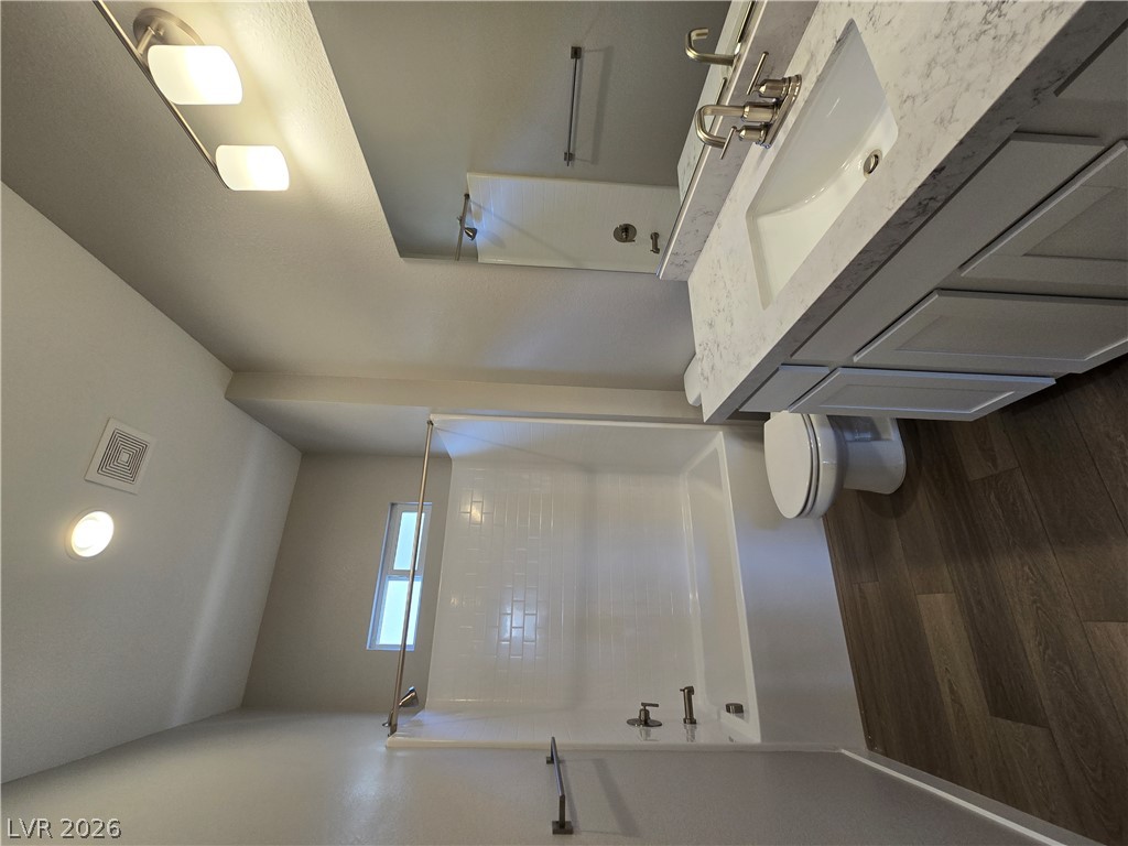 852 Weston Ridge Street Henderson, NV 89011 - Photo 10 of 28 A well-appointed bathroom features a bright vanity with dual sinks, complementing the rich wood flooring.