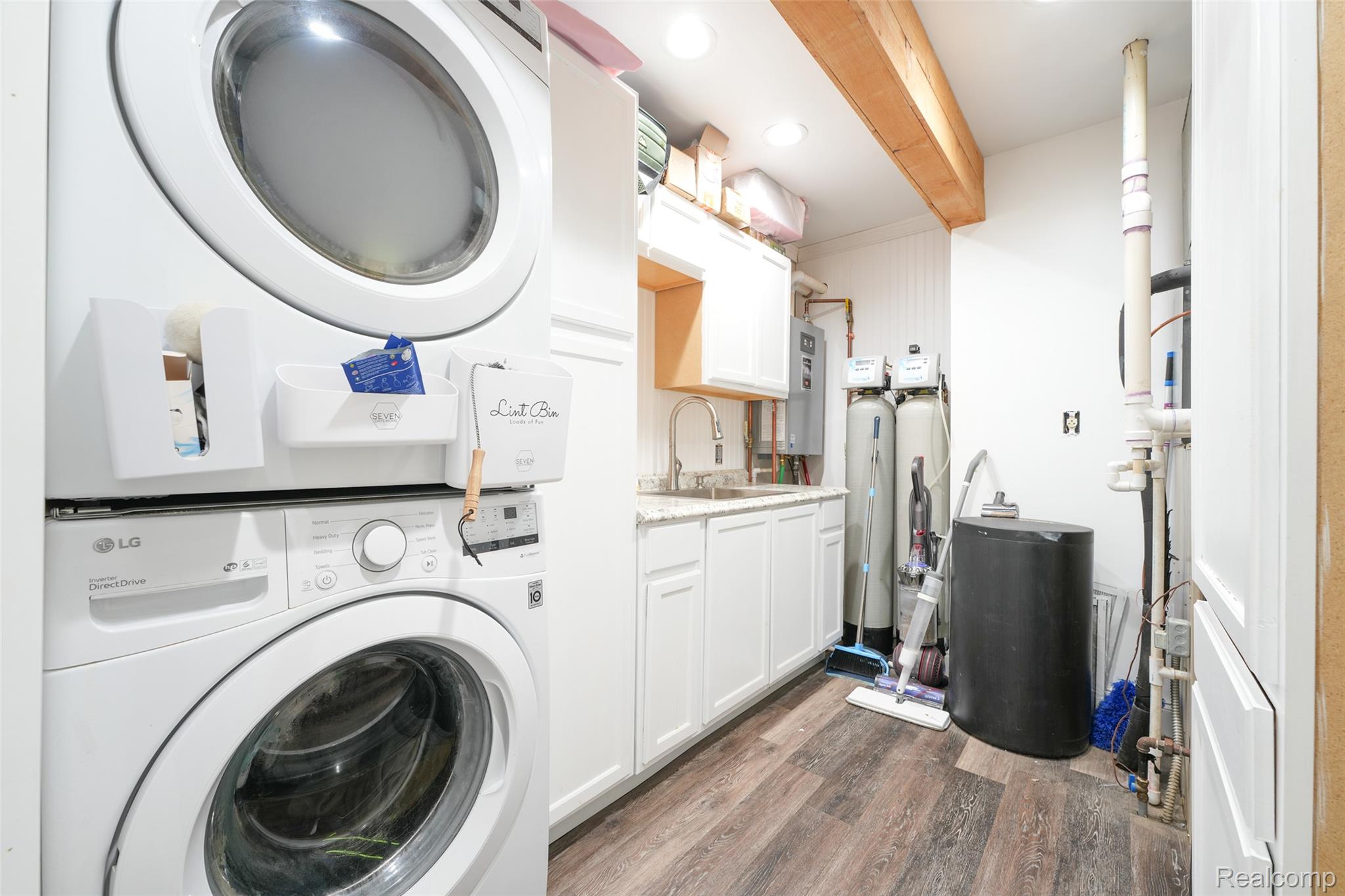9820 Oakhurst Road Holly, MI 48442 - Photo 13 of 16 Laundry area with stacked washer / dryer, dark wood finished floors, cabinet space, and beam ceiling