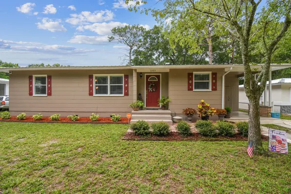 a front view of house with yard and trees in the background