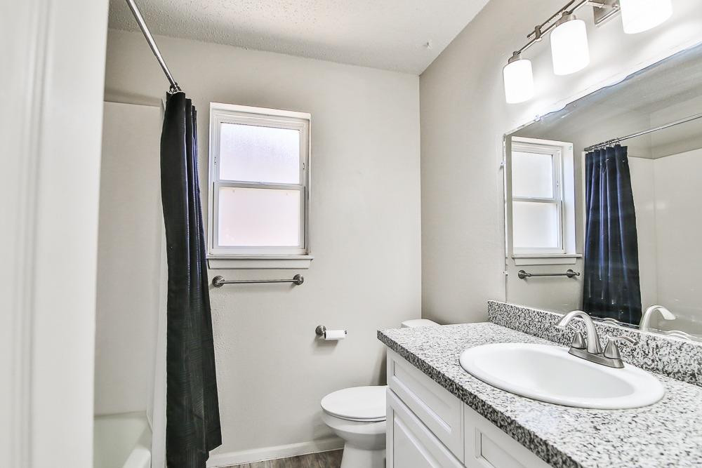 5503 1st Place Lubbock, TX 79416 - Photo 13 of 27 a bathroom with a granite countertop sink toilet a mirror and window