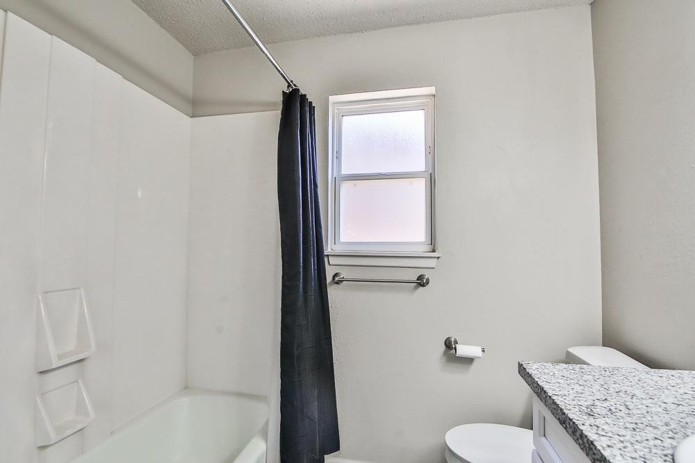 5503 1st Place Lubbock, TX 79416 - Photo 14 of 27 a bathroom with a granite countertop sink toilet and shower