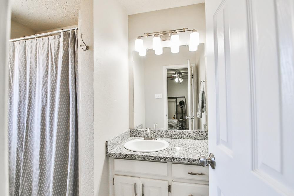 5503 1st Place Lubbock, TX 79416 - Photo 22 of 27 a bathroom with a granite countertop sink and a mirror