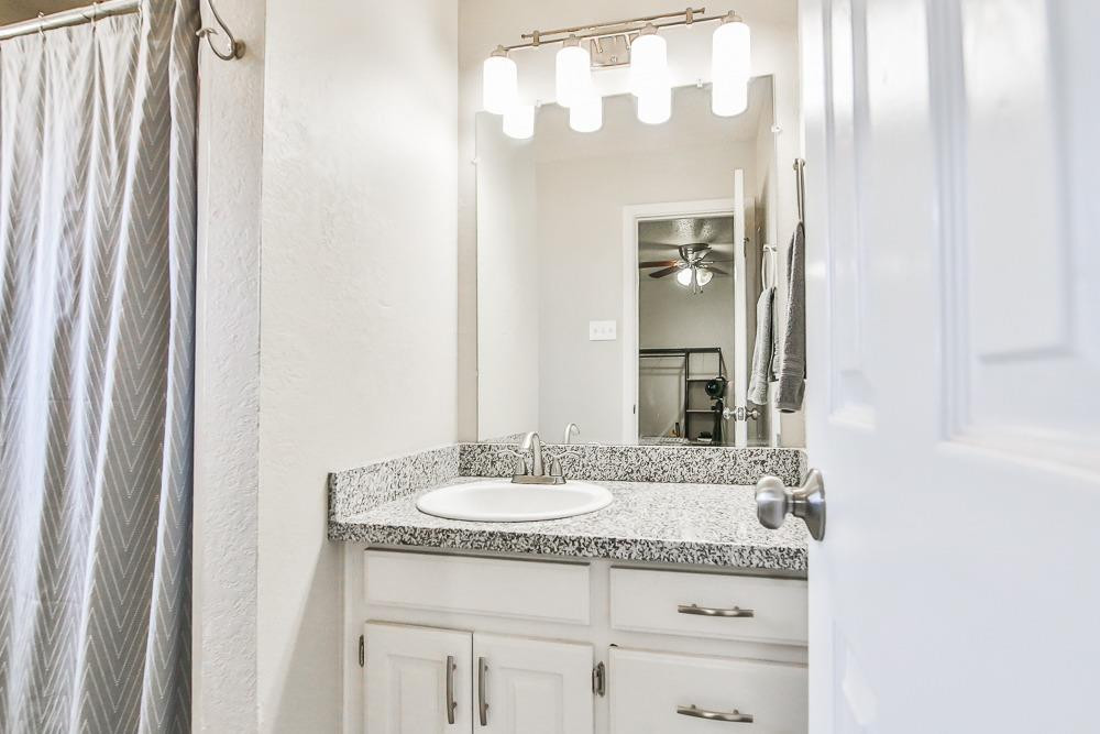5503 1st Place Lubbock, TX 79416 - Photo 23 of 27 a bathroom with a granite countertop sink and a mirror