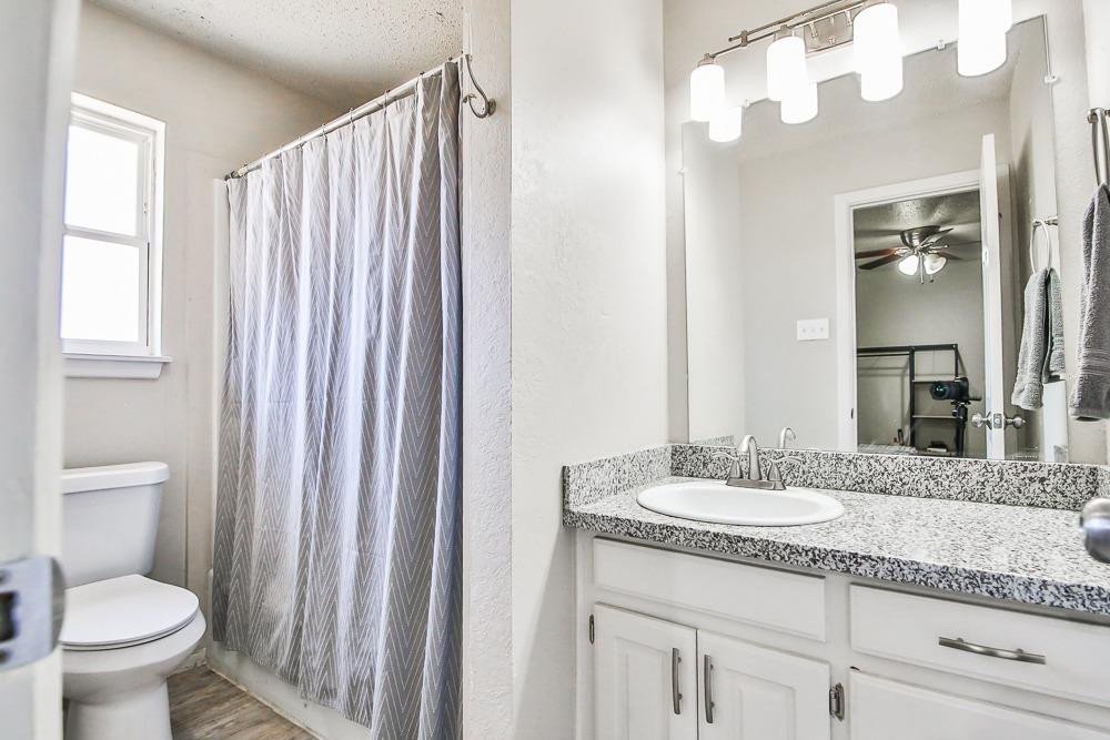 5503 1st Place Lubbock, TX 79416 - Photo 24 of 27 a bathroom with a granite countertop sink toilet and a mirror