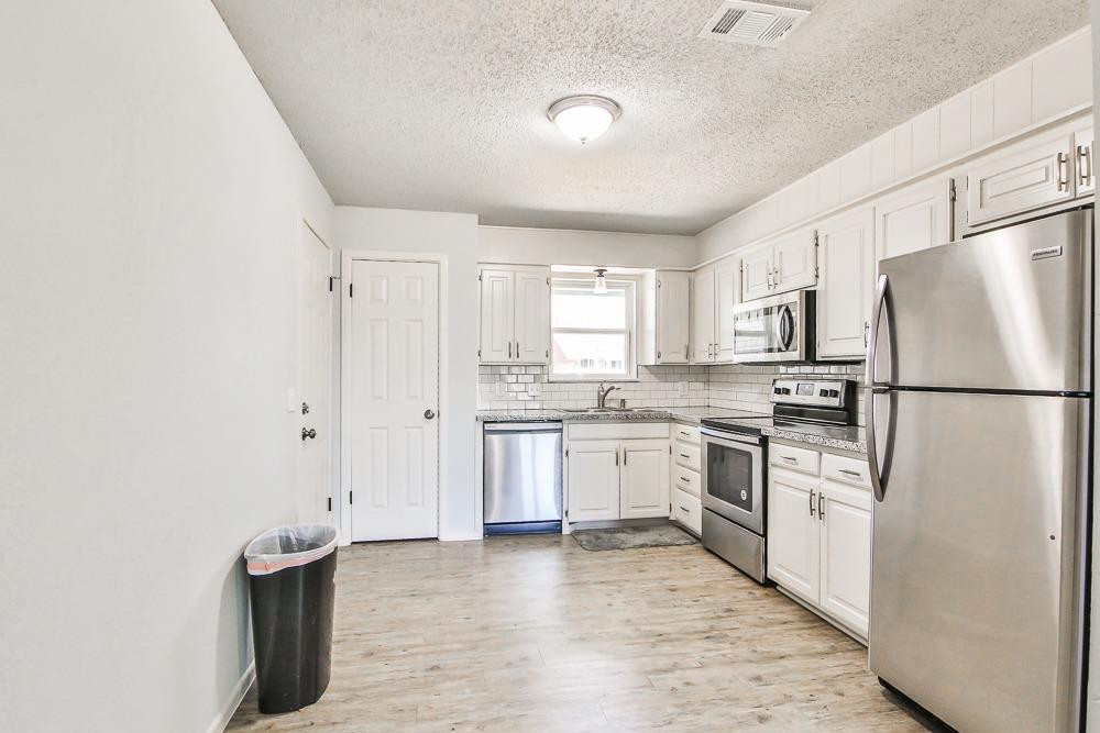 5503 1st Place Lubbock, TX 79416 - Photo 7 of 27 a kitchen with white cabinets and white appliances