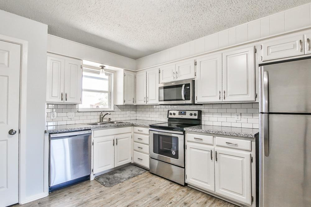 5503 1st Place Lubbock, TX 79416 - Photo 8 of 27 a kitchen with white cabinets sink and stainless steel appliances