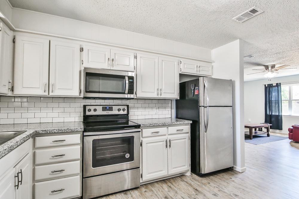 5503 1st Place Lubbock, TX 79416 - Photo 9 of 27 a kitchen with white cabinets and stainless steel appliances
