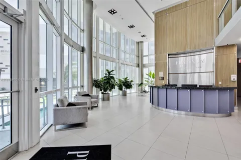 a living room with furniture a large window and potted plants
