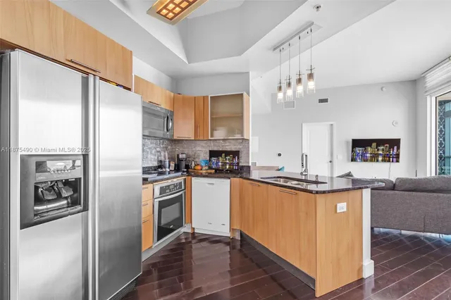 a kitchen with stainless steel appliances granite countertop a refrigerator a stove and a sink with wooden floor