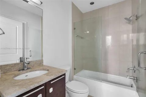 a bathroom with a granite countertop sink toilet a mirror and shower