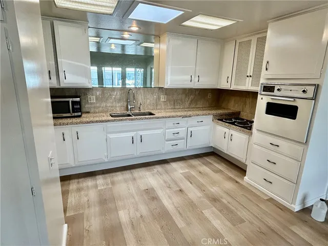 a kitchen with granite countertop a sink a stove and cabinets