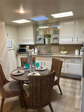 a kitchen with stainless steel appliances granite countertop a dining table chairs and a refrigerator