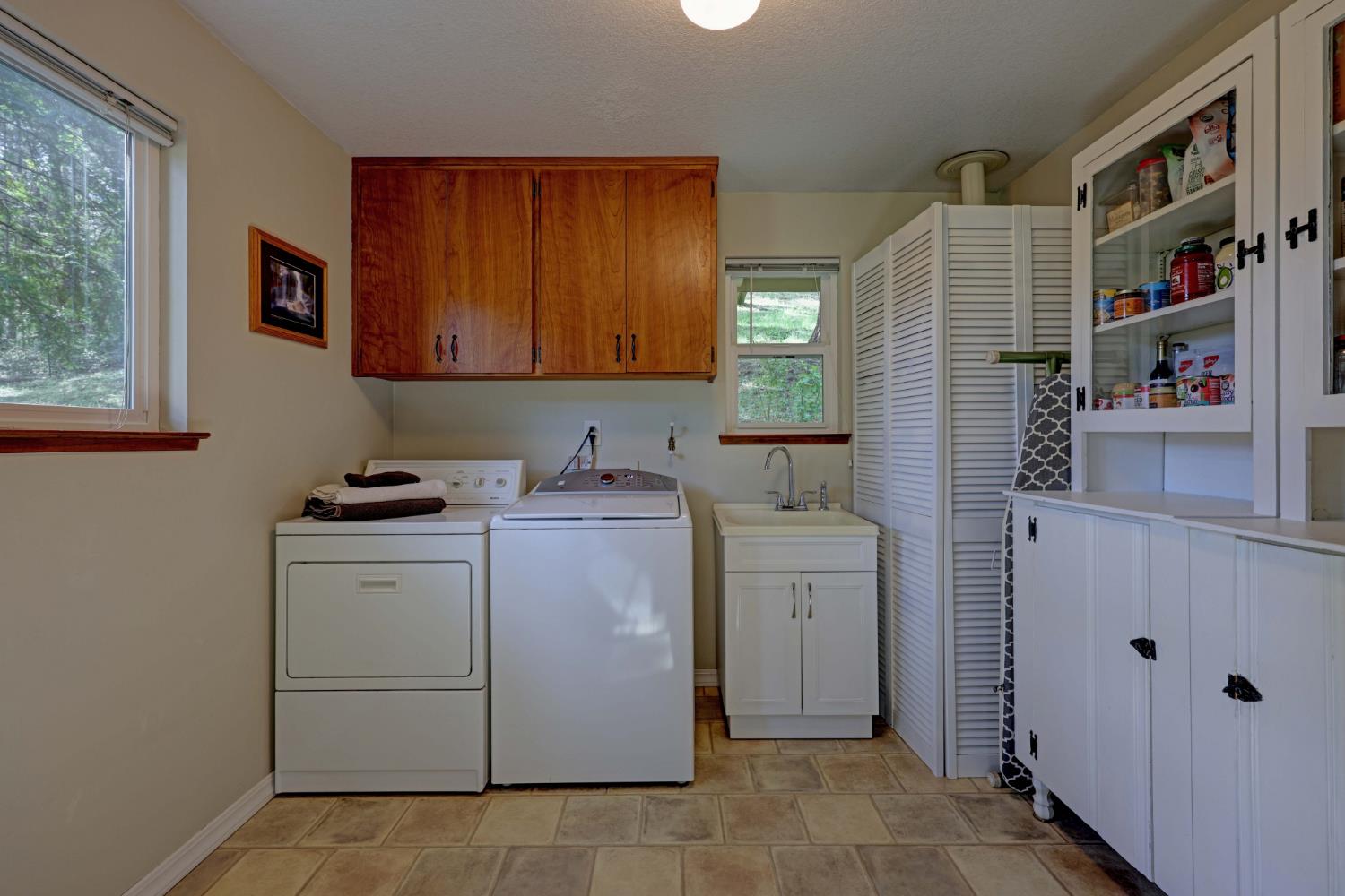 409 Live Oak Road Colfax, CA 95713 - Photo 36 of 74 The cabinet on the right has been a great pantry cabinet for the sellers. It remains with the home and was part of the original kitchen cabinets before their big remodel. In the underhouse work rm/storage is another one showing the wood prior to painting. Seller also had a desk in here but had removed it so you will see it virtually added in the next photo.