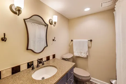 a bathroom with a sink vanity mirror and toilet