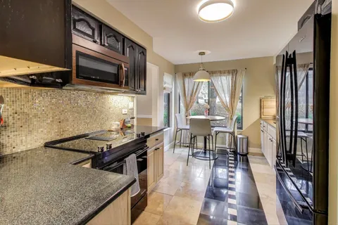 a kitchen with stainless steel appliances granite countertop a stove top oven a sink dishwasher a dining table and chairs with wooden floor