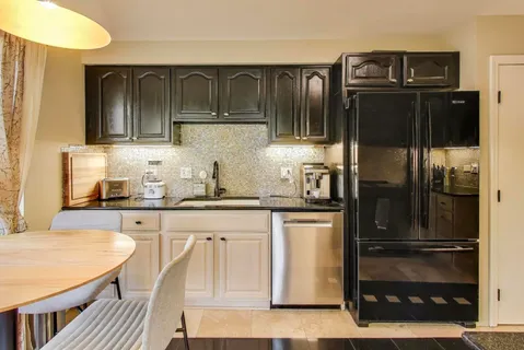 a kitchen with granite countertop a refrigerator and cabinets