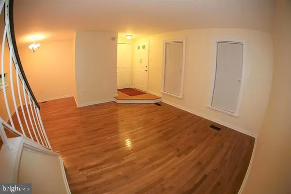 a view of an empty room with wooden floor and a bathroom
