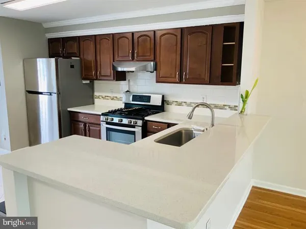 a kitchen with stainless steel appliances a refrigerator a sink and white cabinets