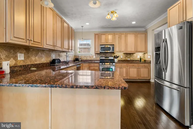 a kitchen with stainless steel appliances granite countertop a stove top oven a sink a dining table and chairs with wooden floor