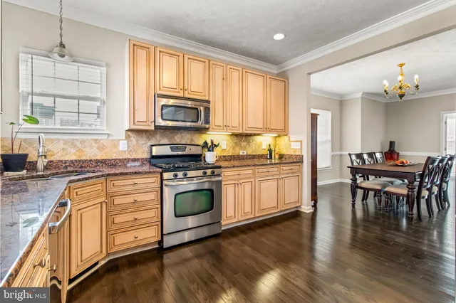 a kitchen with stainless steel appliances granite countertop a refrigerator dining table and chairs