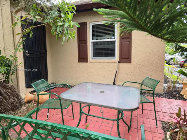 a patio with table and chairs and potted plants