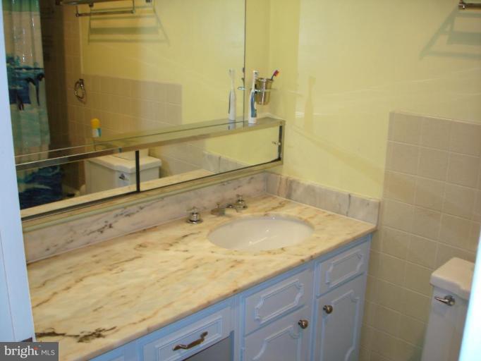 4401 Roland Avenue, Unit 607 Baltimore, MD 21210 - Photo 14 of 16 a bathroom with a granite countertop sink and a mirror