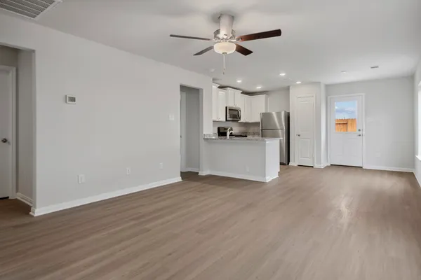 a view of a kitchen with a sink a refrigerator and wooden floor