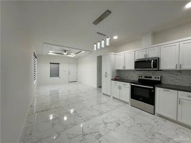 a large kitchen with granite countertop a stove a sink a microwave and cabinets