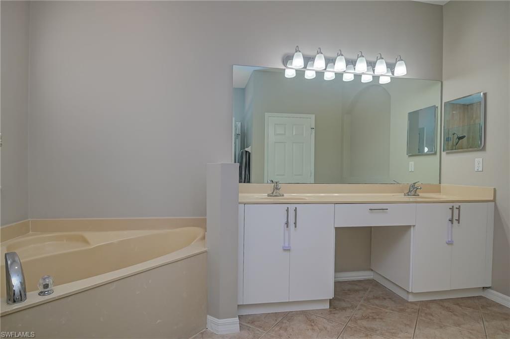 7658 Bristol Circle Naples, FL 34120 - Photo 17 of 32 a bathroom with a tub sink and mirror