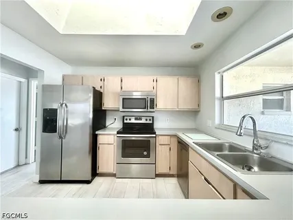 a kitchen with stainless steel appliances granite countertop a sink a stove a refrigerator with grey cabinets