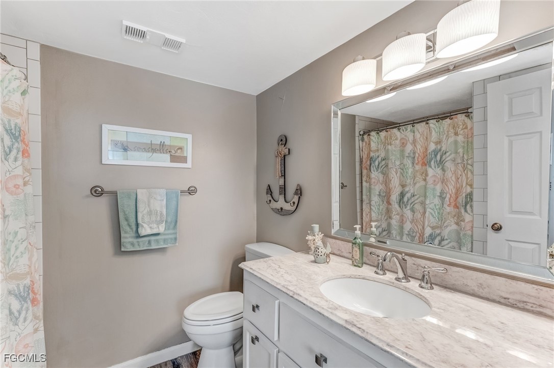 16007 Davis Road, Unit 524 Fort Myers, FL 33908 - Photo 16 of 36 a bathroom with a granite countertop sink a toilet and a mirror