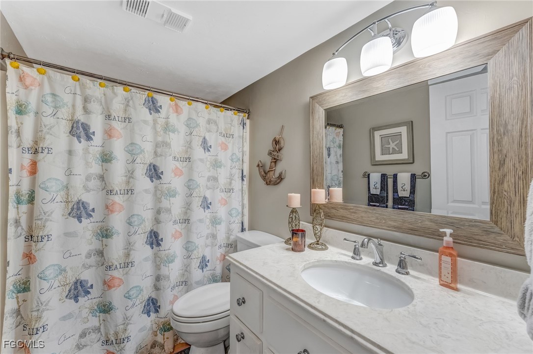 16007 Davis Road, Unit 524 Fort Myers, FL 33908 - Photo 19 of 36 a bathroom with a granite countertop sink a toilet and a mirror