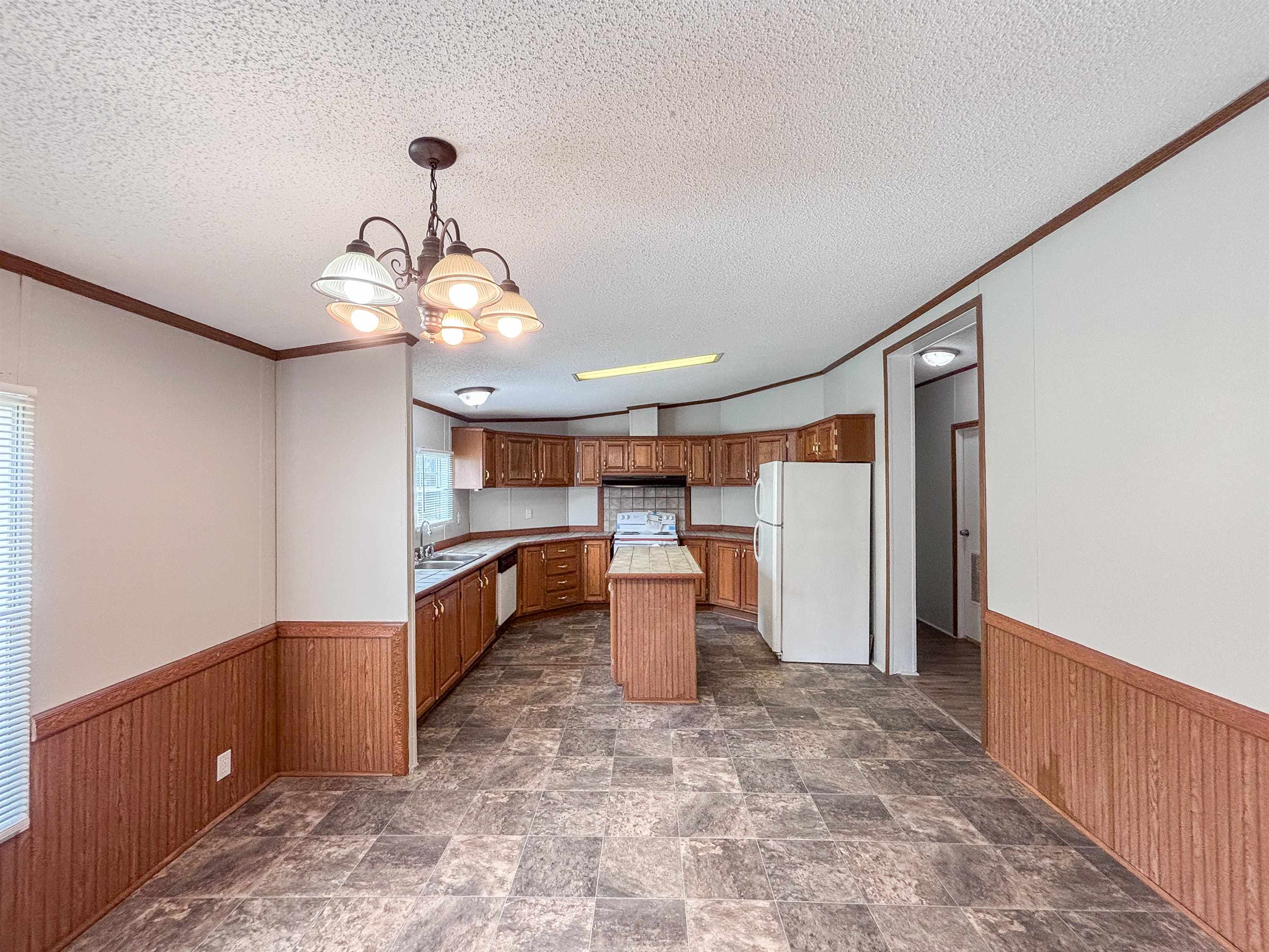2847 Holly Grove Road Covington, TN 38019 - Photo 10 of 36 Open-concept kitchen and dining area featuring a central island, wood-finish cabinetry, and durable tile-look flooring