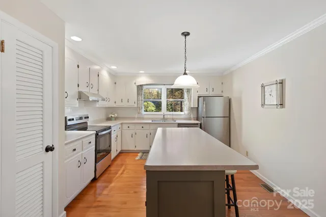 a kitchen with kitchen island a counter space a sink appliances and cabinets