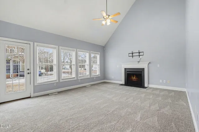 an empty room with windows and fireplace