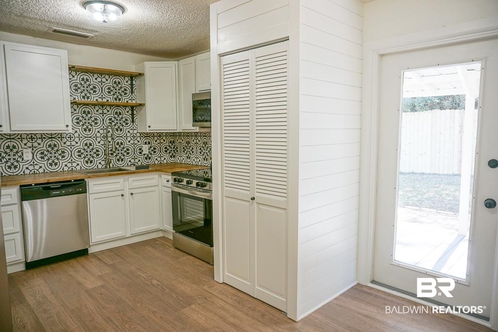 4159 Rebecca Road Mobile, AL 36609 - Photo 7 of 19 Kitchen with visible vents, appliances with stainless steel finishes, white cabinets, butcher block countertops, and light wood-type flooring