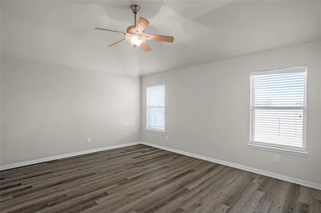 an empty room with wooden floor fan and window