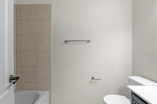 a bathroom with a granite countertop toilet and a bathtub