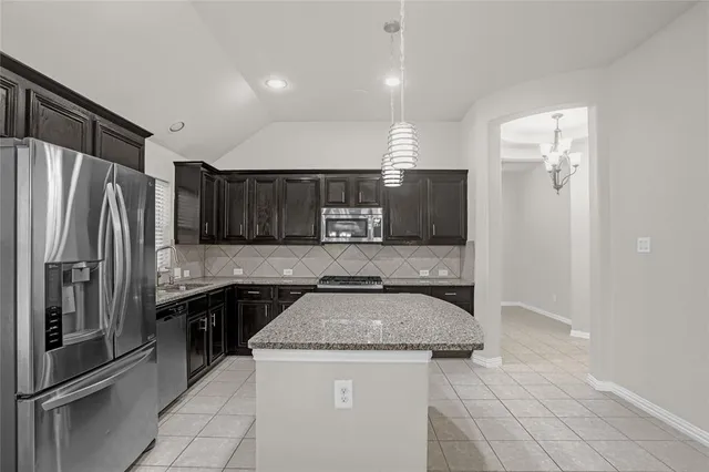a kitchen with stainless steel appliances granite countertop a sink and a refrigerator