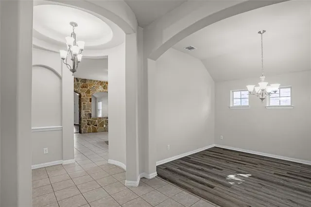 a view of a livingroom with a chandelier fan and kitchen view