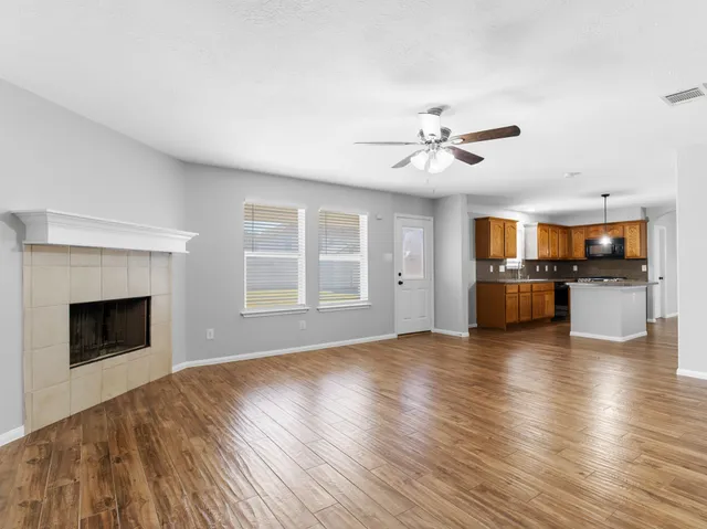 a view of an empty room with a kitchen and a fireplace