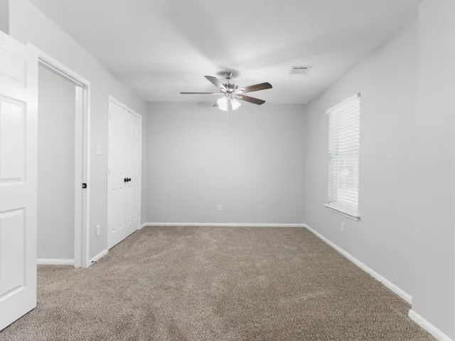 an empty room with windows and fan